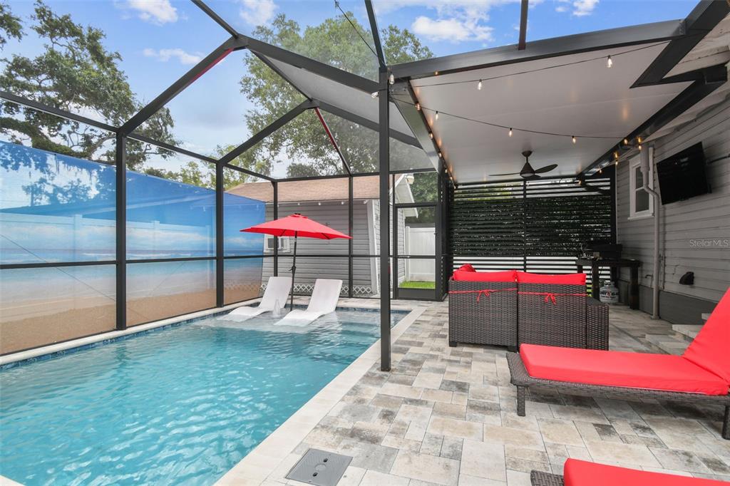 A screened-in patio features a swimming pool with lounge chairs and outdoor seating — 904 E HAMILTON AVENUE, TAMPA, FL