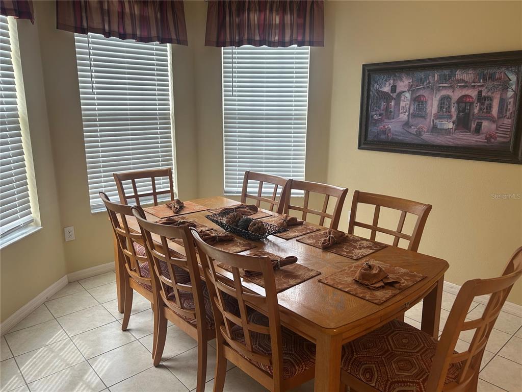 A dining room features a wooden table with six chairs, tiled flooring, and window blinds — 190 MINNIEHAHA CIRCLE, HAINES CITY, FL