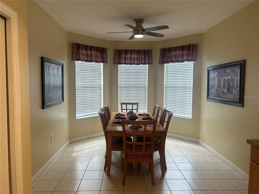 A dining area features a wooden table with six chairs, tile flooring, and three windows — 190 MINNIEHAHA CIRCLE, HAINES CITY, FL