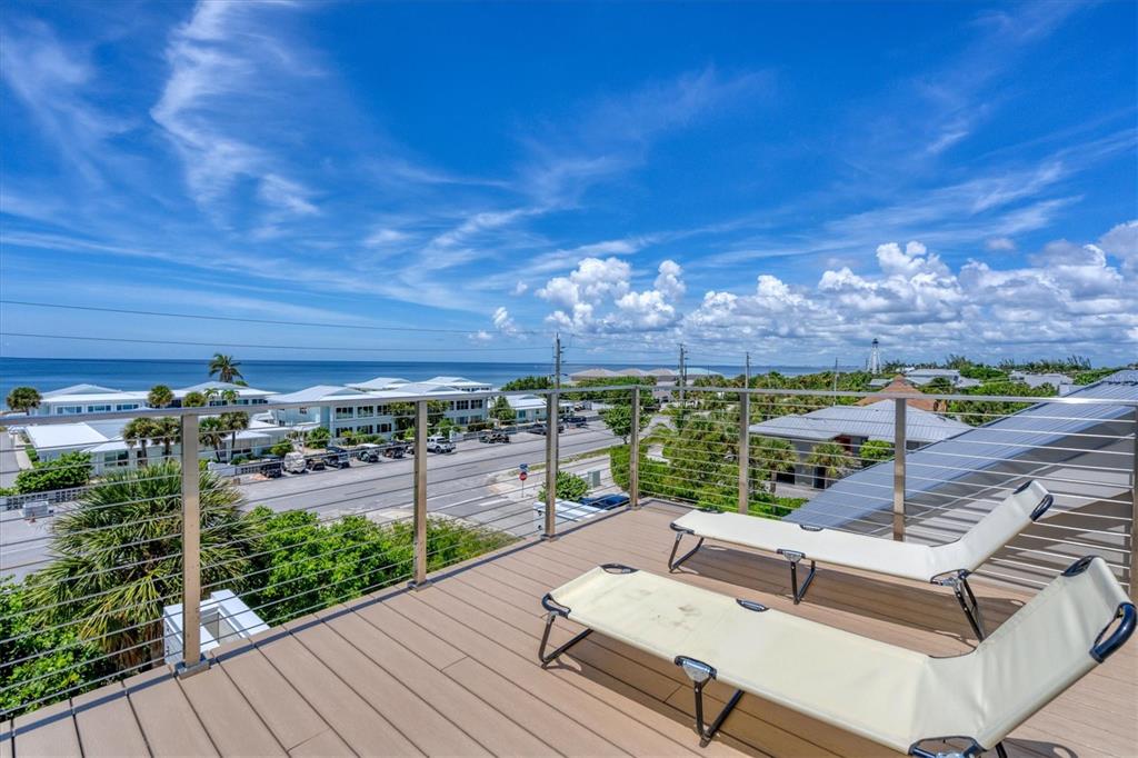 A rooftop deck features two lounge chairs, a metal cable railing, and a coastal view — 300 GASPARILLA STREET, BOCA GRANDE, FL