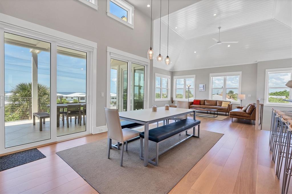 A bright dining and living area with vaulted ceilings, hardwood floors, and large glass doors — 300 GASPARILLA STREET, BOCA GRANDE, FL