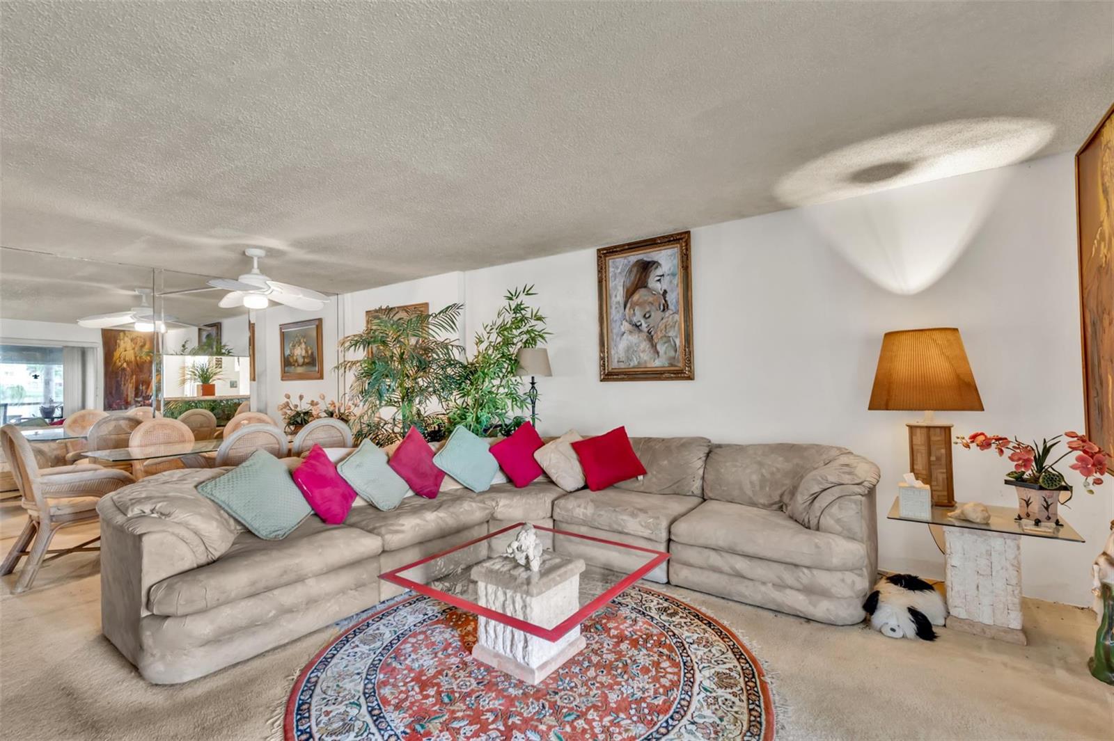 A living room features a beige sectional sofa, a glass coffee table, and a round rug — 121 SE 3rd Avenue # 104, Dania Beach FL 33004, DANIA BEACH, FL