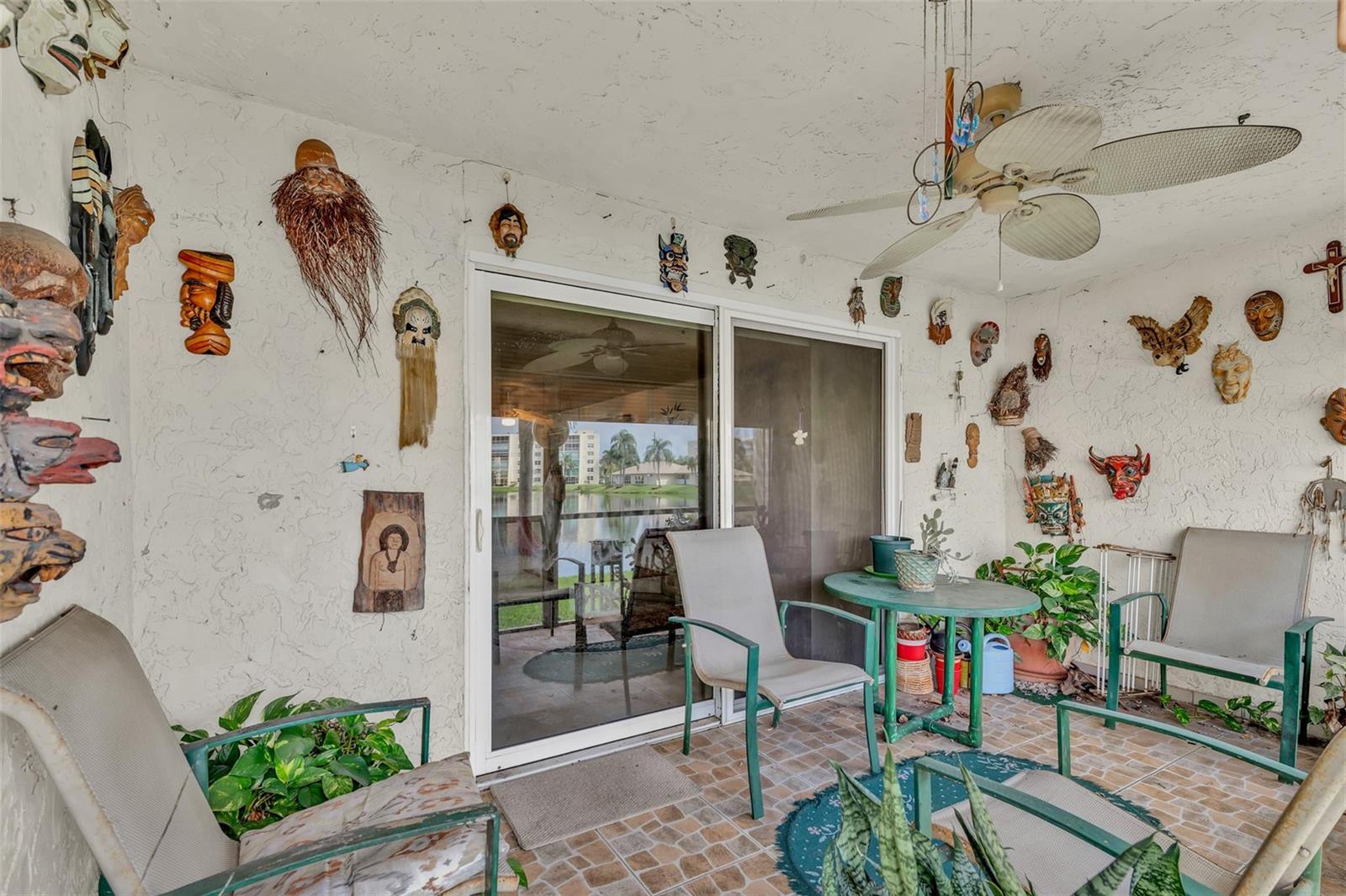A covered patio features a tiled floor, outdoor furniture, and numerous decorative masks on the walls — 121 SE 3rd Avenue # 104, Dania Beach FL 33004, DANIA BEACH, FL