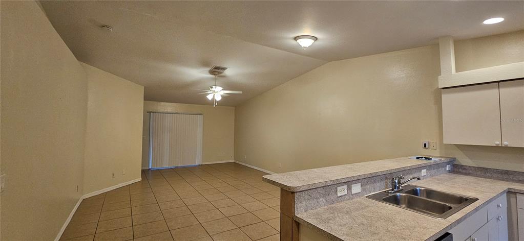 A kitchen with a breakfast bar overlooks an open-concept living area with tile flooring — 1628 SW SANTA BARBARA PLACE, CAPE CORAL, FL