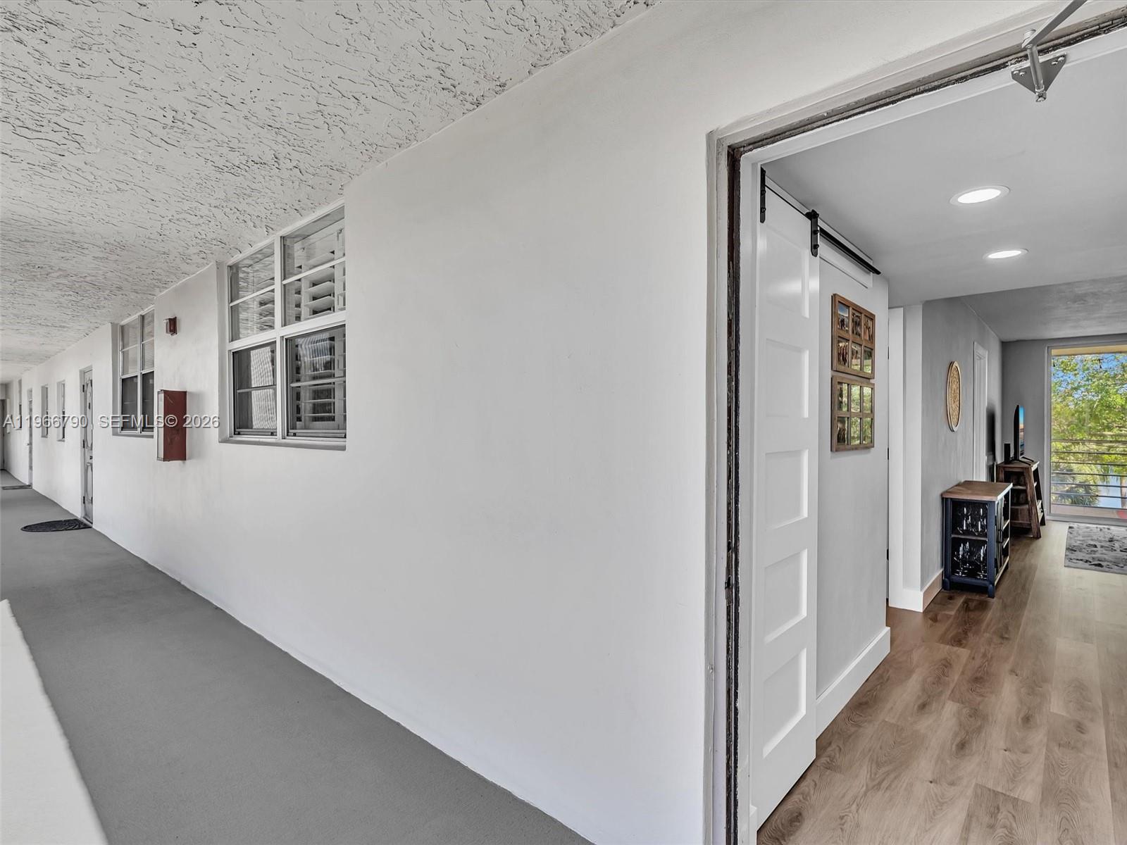 A view from an exterior walkway looking into a room with wood-look flooring — 9340 Lagoon Pl # 303, Davie FL 33324, DAVIE, FL
