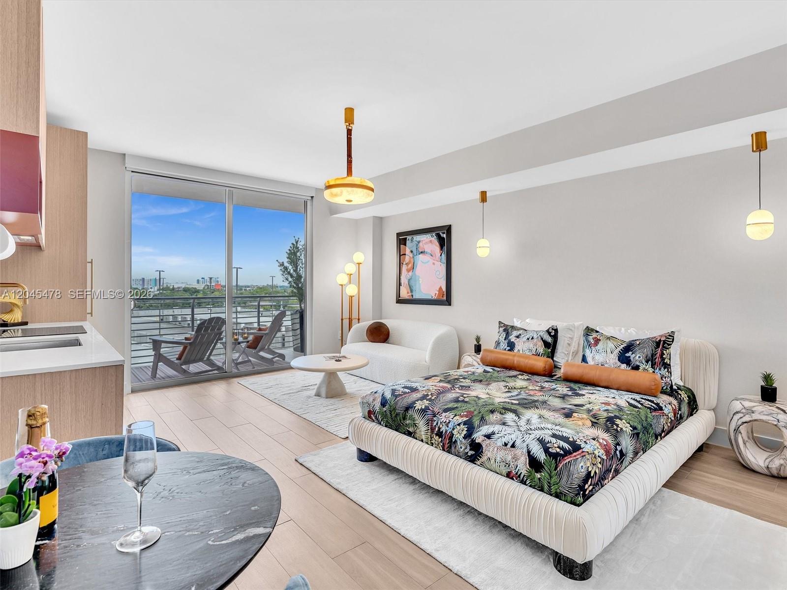 A studio apartment features a bed, small seating area, and a balcony with city views — 90 NE 32nd st # 724, Miami FL 33137, MIAMI, FL