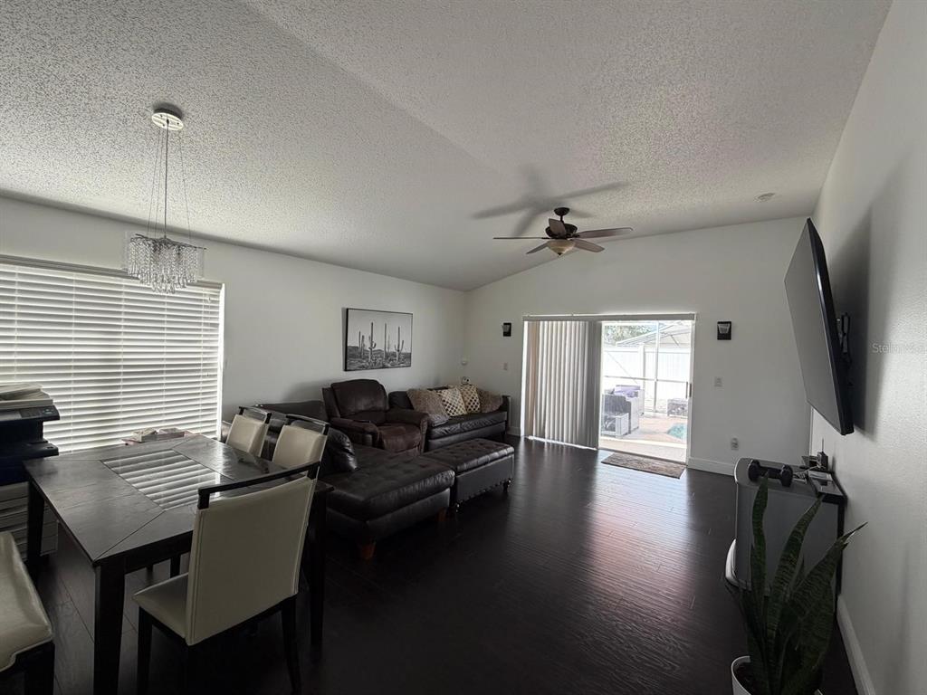 A living and dining area features dark wood floors, a ceiling fan, and sliding glass doors — 2558 E CHATMAN CIRCLE, KISSIMMEE, FL