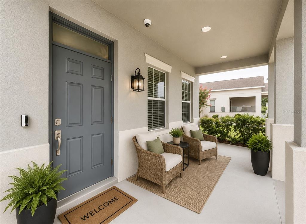A covered front porch features a gray door, two wicker chairs, and potted plants — 1185 SEBURN ROAD, APOPKA, FL