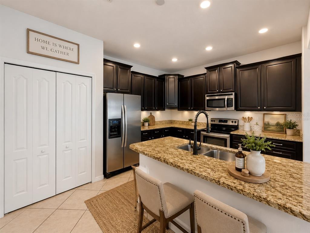 A kitchen features dark wood cabinets, granite countertops, stainless steel appliances, and a breakfast bar — 1185 SEBURN ROAD, APOPKA, FL