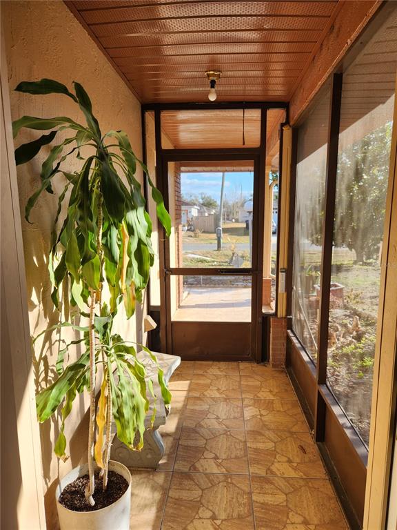 A screened-in porch features tiled flooring, a potted plant, a bench, and a screen door — 713 BEAR WAY, KISSIMMEE, FL