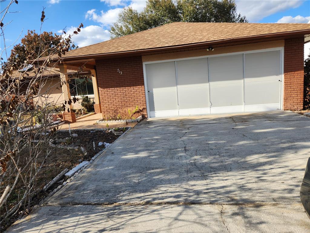 A single-story brick house features a large garage with sliding doors and a concrete driveway — 713 BEAR WAY, KISSIMMEE, FL