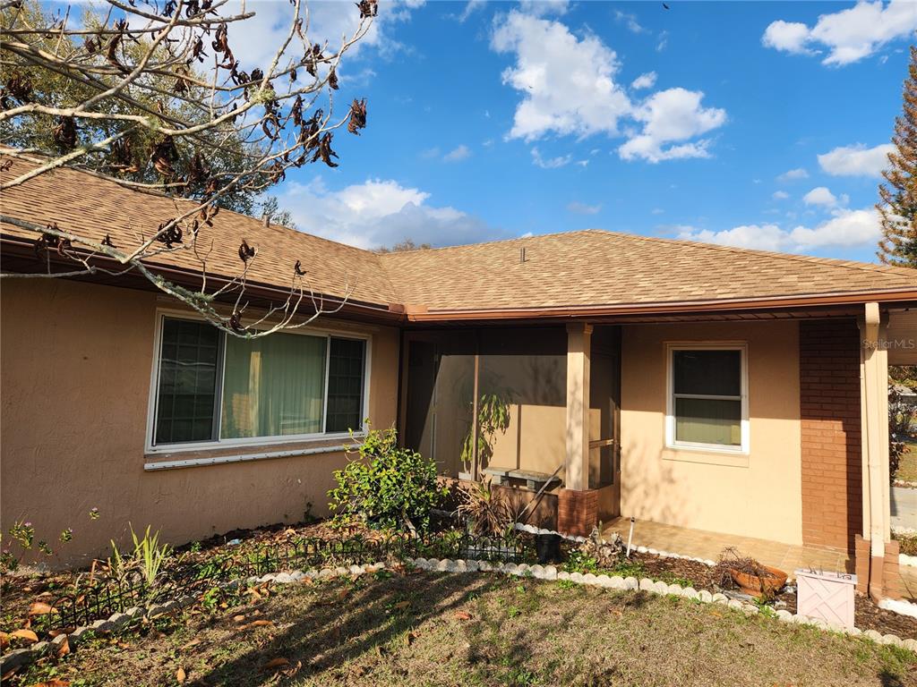 A tan house exterior features a screened-in porch, a large window, and a shingled roof — 713 BEAR WAY, KISSIMMEE, FL
