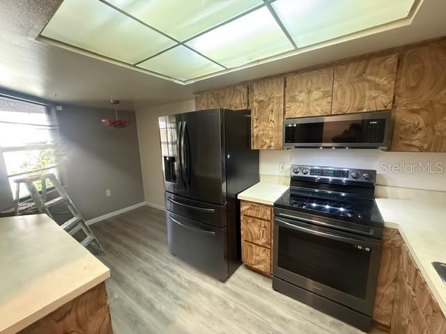 A kitchen features wood-grain cabinets, stainless steel appliances, and light-colored wood-look flooring — 2131 RIDGE ROAD S UNIT 74, LARGO, FL