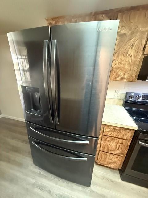 A stainless steel Samsung French door refrigerator stands in a kitchen with wood-patterned cabinets — 2131 RIDGE ROAD S UNIT 74, LARGO, FL