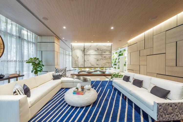 A modern living room features two white sofas, a round coffee table, and wood-paneled walls — 55 SW 9th St # 1001, Miami FL 33130, MIAMI, FL