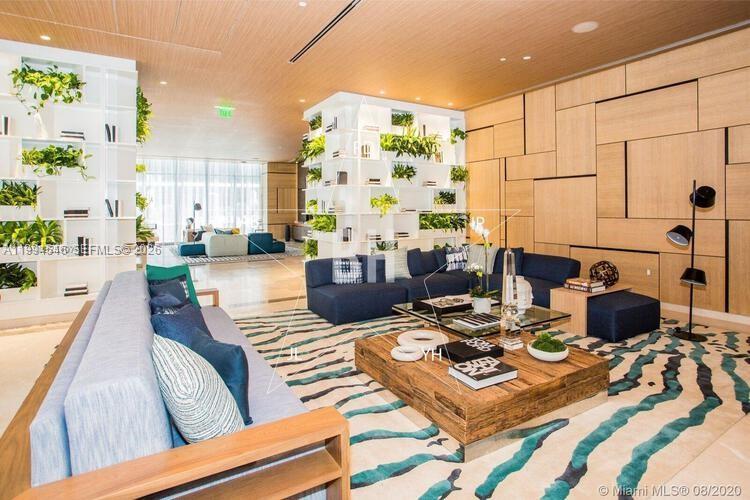 A modern lounge area features a blue sectional sofa, wooden coffee table, and white shelving — 55 SW 9th St # 1001, Miami FL 33130, MIAMI, FL