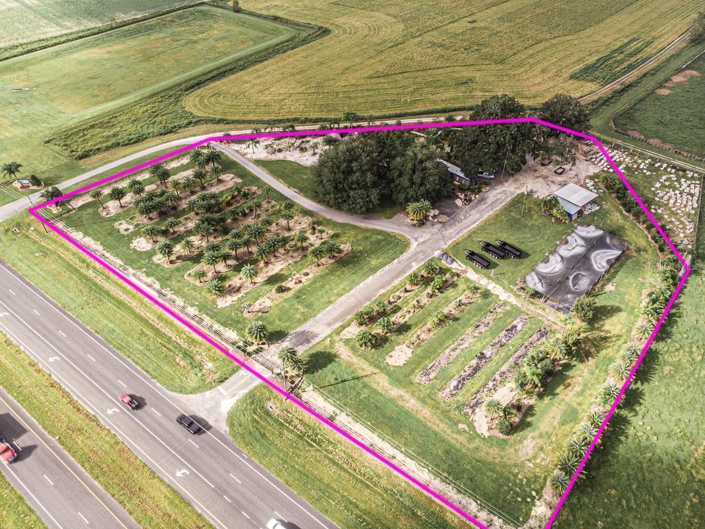 An aerial view shows a property with a plant nursery, trees, and buildings near a highway — 13494 N US HWY 301, OXFORD, FL