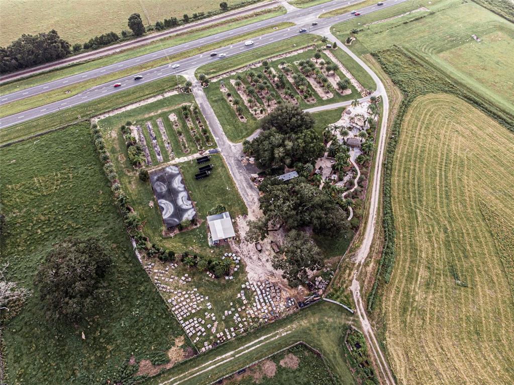 An aerial view shows a property with a nursery, large trees, and a highway nearby — 13494 N US HWY 301, OXFORD, FL