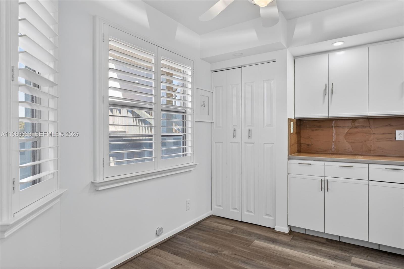 A room features white cabinets, a brown backsplash, louvered window shutters, and wood-look flooring — 1802 Eleuthera POINT # C3, Coconut Creek FL 33066, COCONUT CREEK, FL