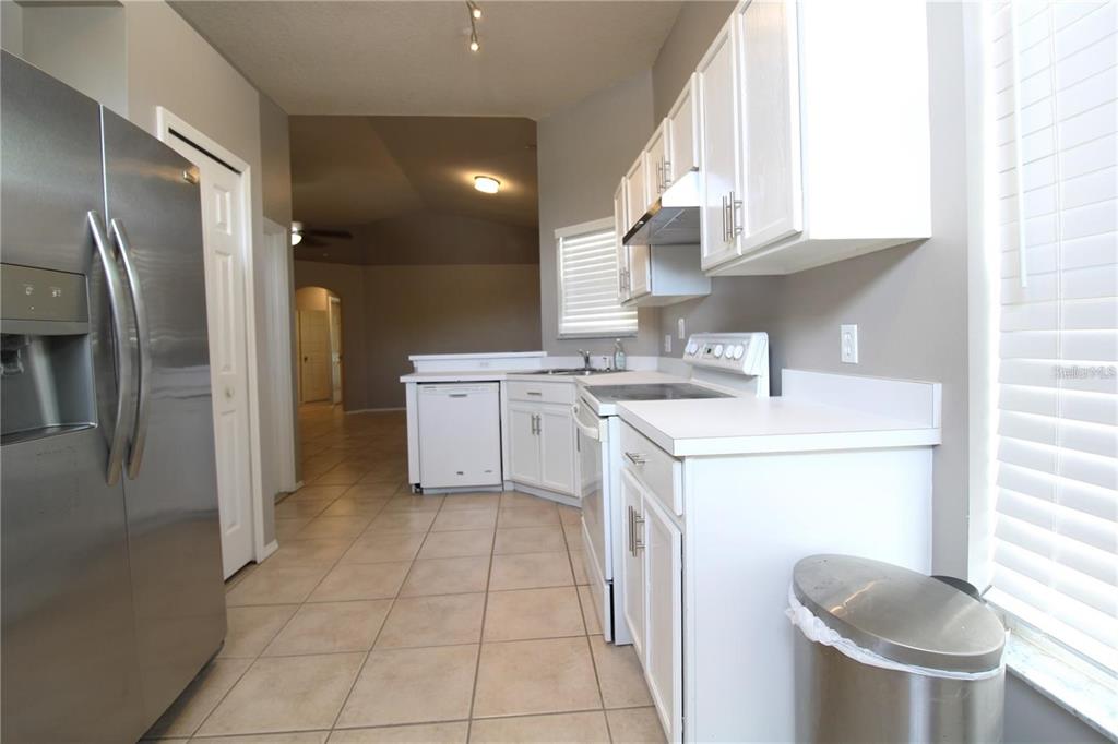 A kitchen features white cabinets, stainless steel appliances, and tile flooring — 464 BRIAR BAY CIRCLE, ORLANDO, FL