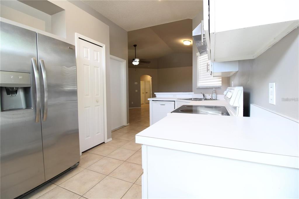 A kitchen features stainless steel appliances, white cabinetry, and light-colored tile flooring — 464 BRIAR BAY CIRCLE, ORLANDO, FL