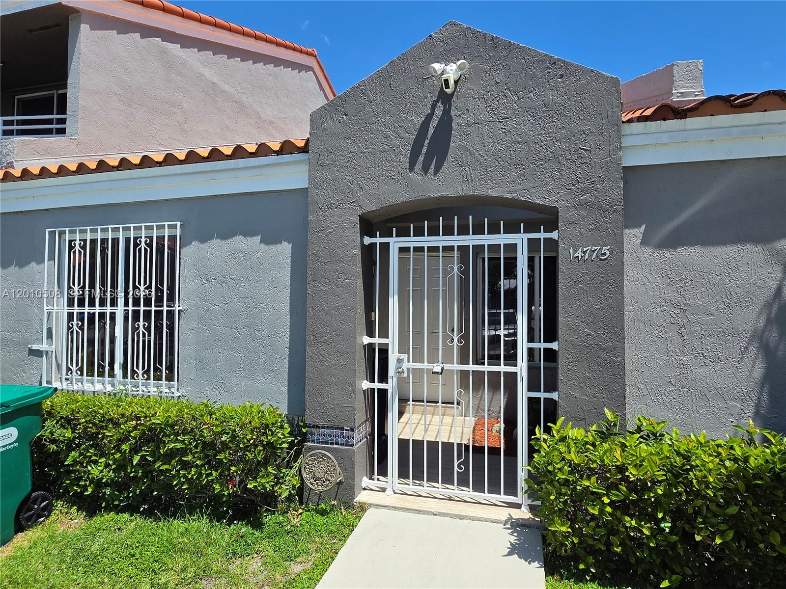 A gray stucco house exterior features a white metal security gate and window bars — 14775 SW 83rd Ln # 14775, Miami FL 33193, MIAMI, FL