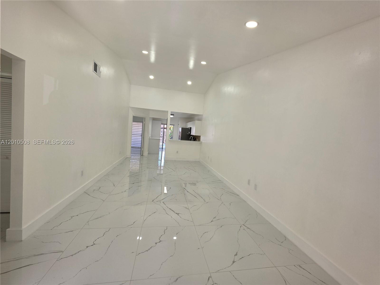 A long, empty room features white walls, recessed lighting, and white marble-patterned tile flooring — 14775 SW 83rd Ln # 14775, Miami FL 33193, MIAMI, FL