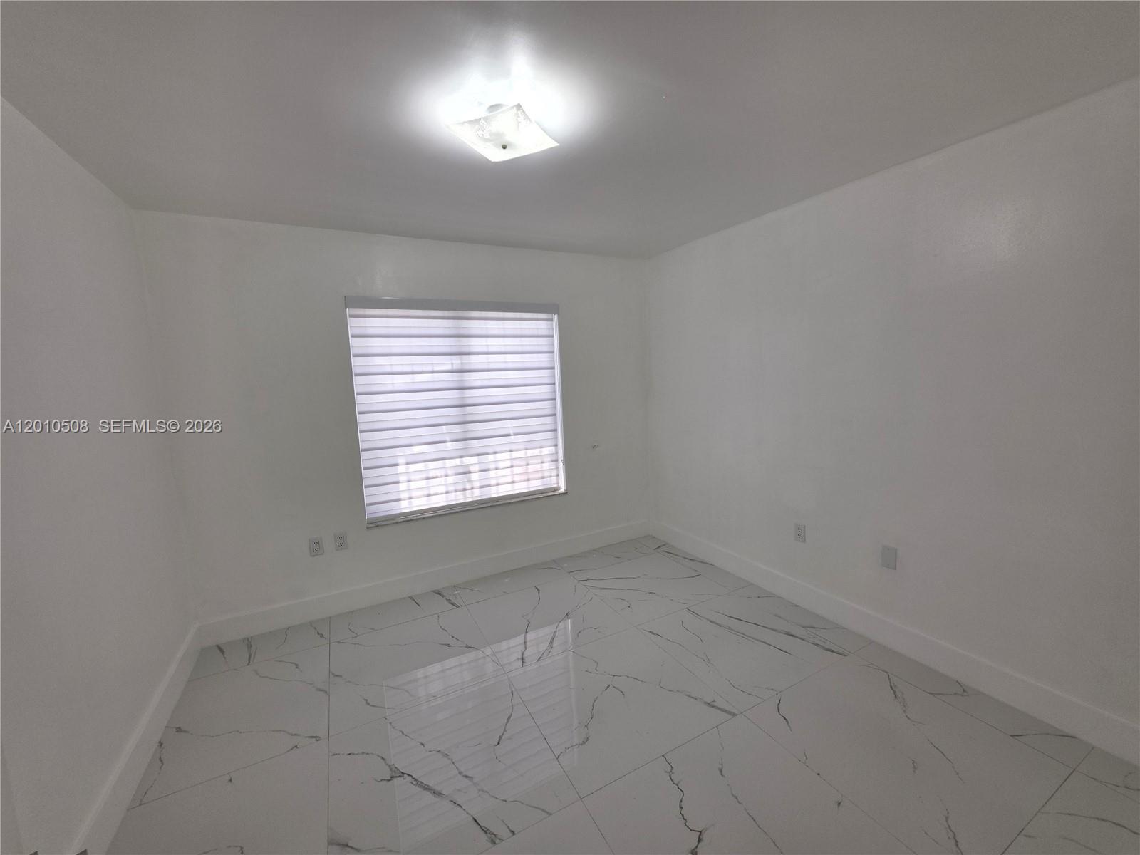 A minimalist room features white walls, a single window with blinds, and marble-patterned tile flooring — 14775 SW 83rd Ln # 14775, Miami FL 33193, MIAMI, FL