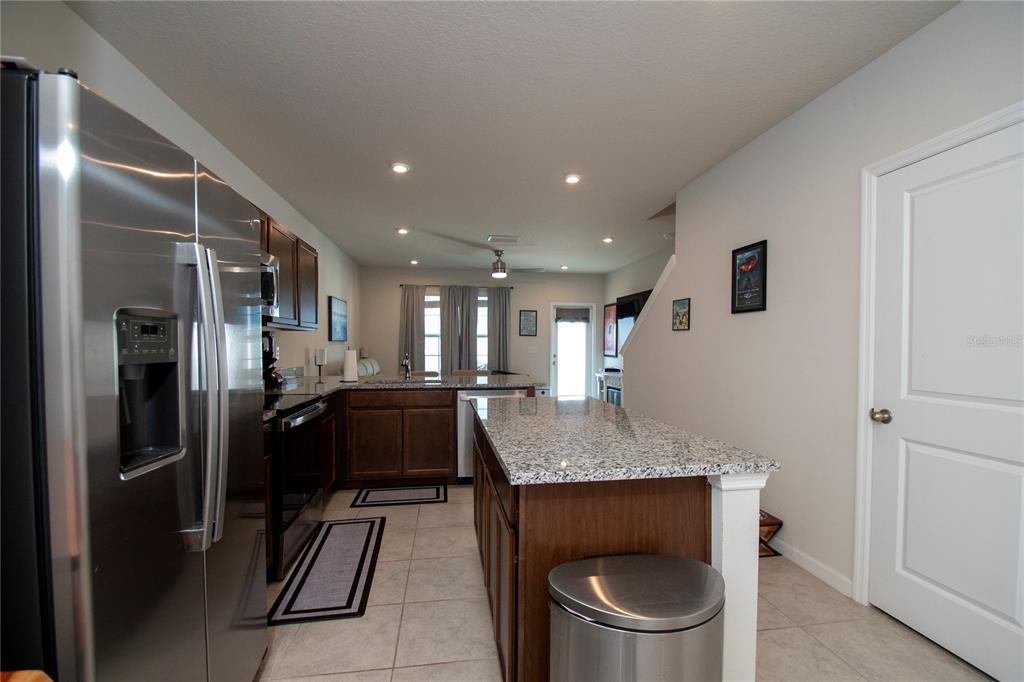 A kitchen features dark wood cabinets, granite countertops, a center island, and stainless steel appliances — 4660 OLD BLUSH STREET, BRADENTON, FL