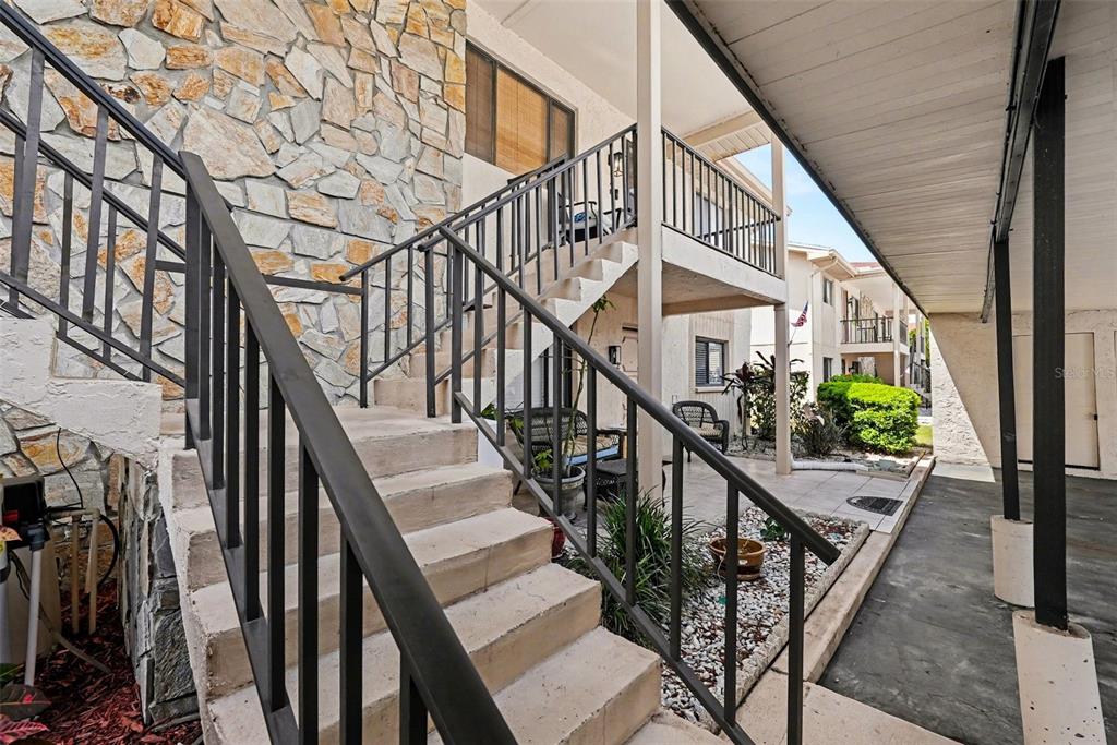 Concrete stairs with black metal railings lead to an upper-level balcony of a residential building — 9990 EAGLES POINT CIRCLE UNIT 4, PORT RICHEY, FL