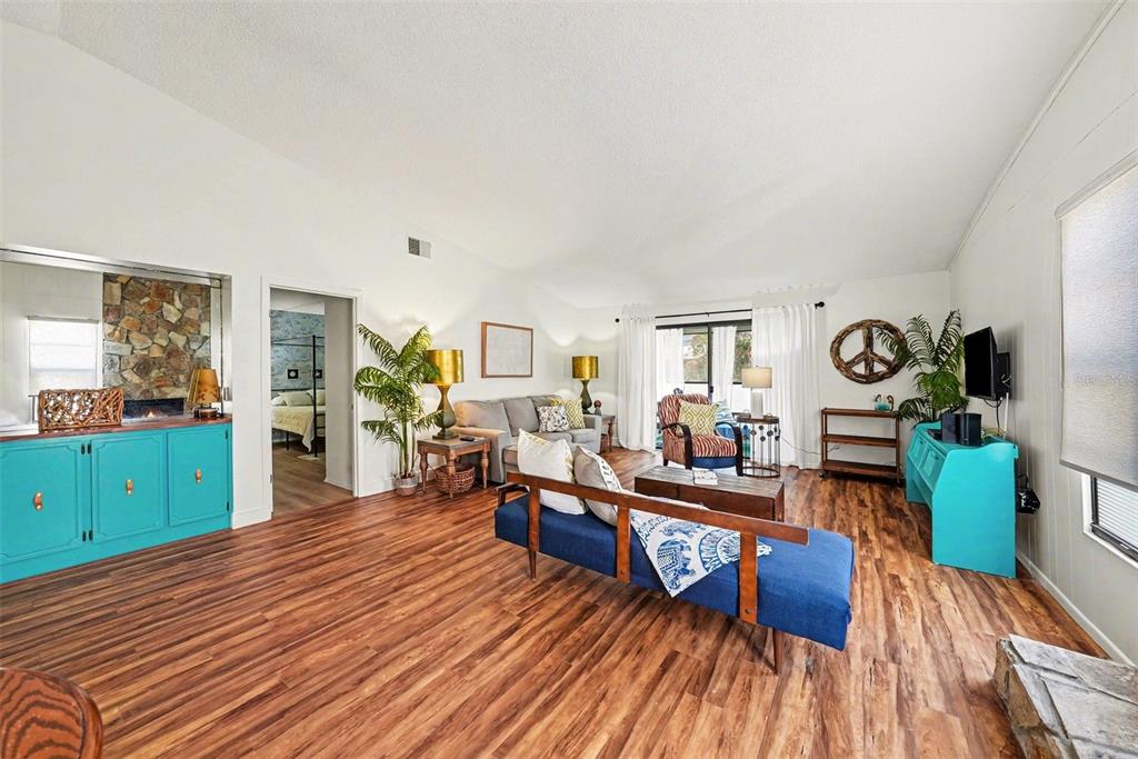 A living room features wood-look flooring, a blue cabinet, a blue sofa, and a fireplace — 9990 EAGLES POINT CIRCLE UNIT 4, PORT RICHEY, FL