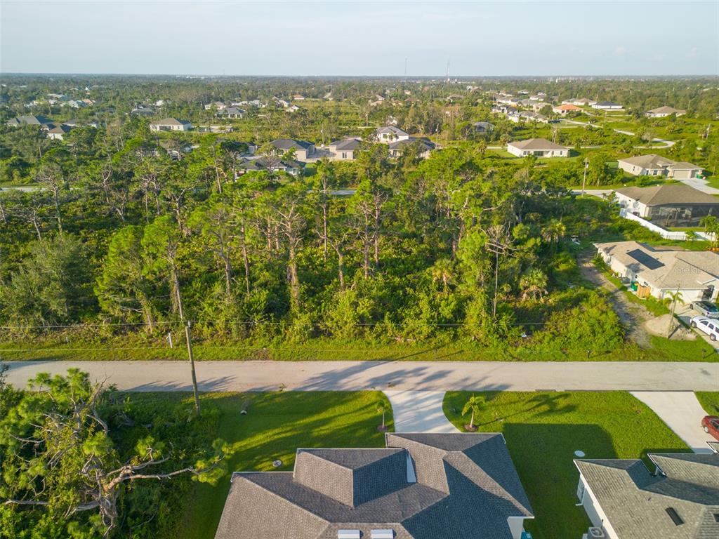 An aerial view shows a residential street with a wooded lot and surrounding houses — 13375 YAGER LANE, PORT CHARLOTTE, FL