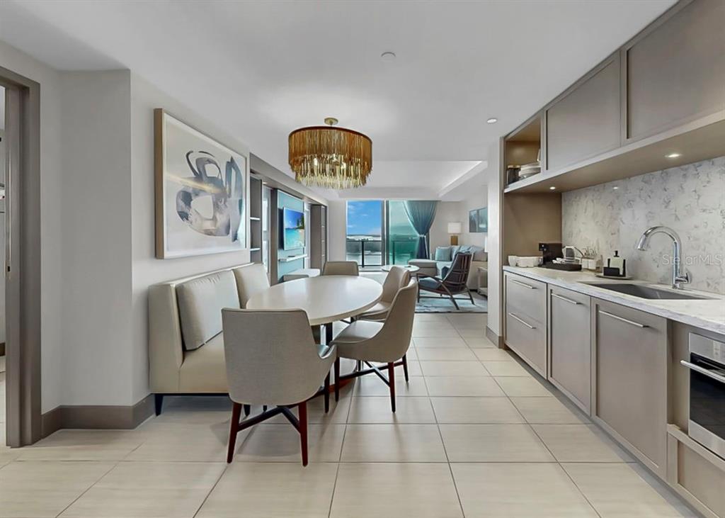 A modern kitchen and dining area with a banquette, round table, and neutral finishes — 691 S GULFVIEW BOULEVARD UNIT 1410, CLEARWATER BEACH, FL