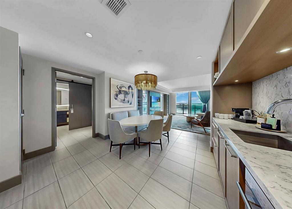 A dining area with a chandelier and a kitchenette with marble countertops and cabinetry — 691 S GULFVIEW BOULEVARD UNIT 1410, CLEARWATER BEACH, FL