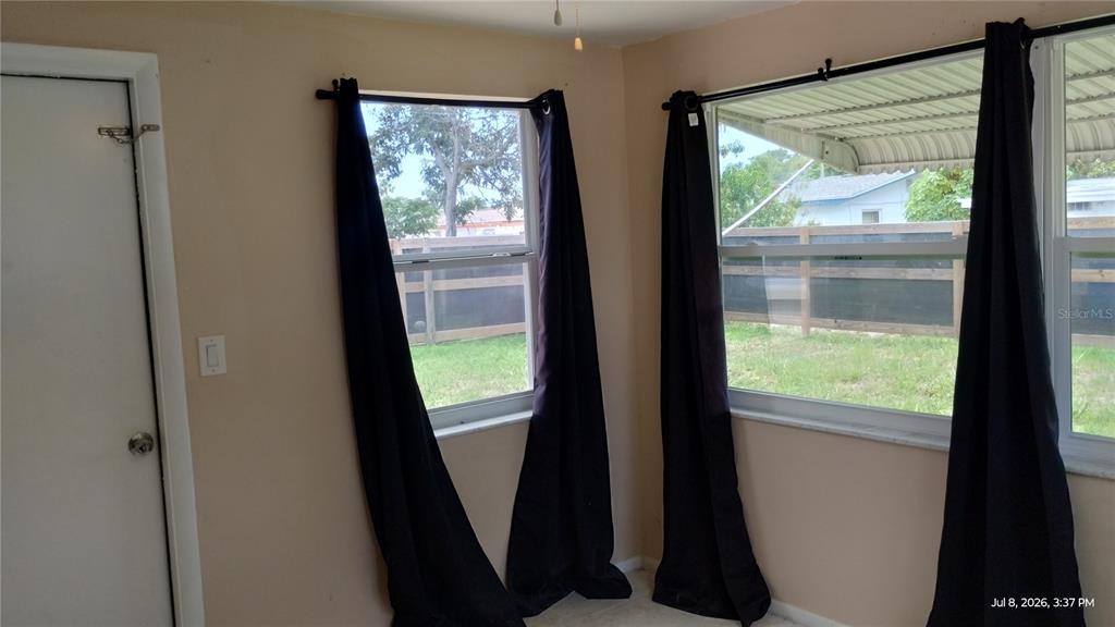 A room with light walls, two windows with black curtains, and a white door — 3637 WINDER DRIVE, HOLIDAY, FL