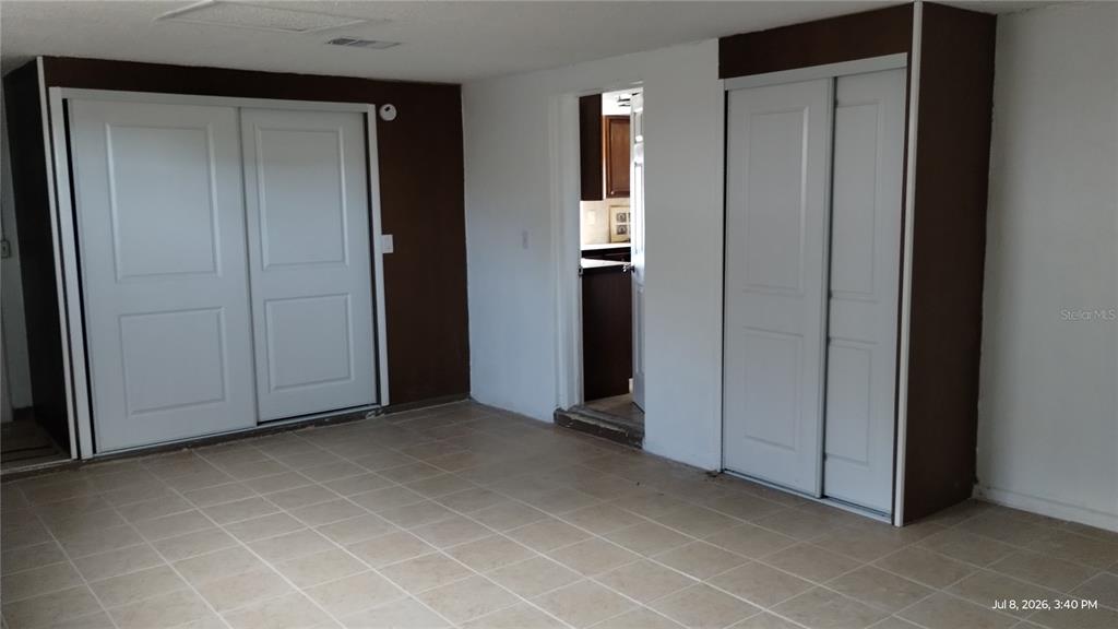A room with tiled flooring, two sets of white sliding closet doors, and a doorway — 3637 WINDER DRIVE, HOLIDAY, FL