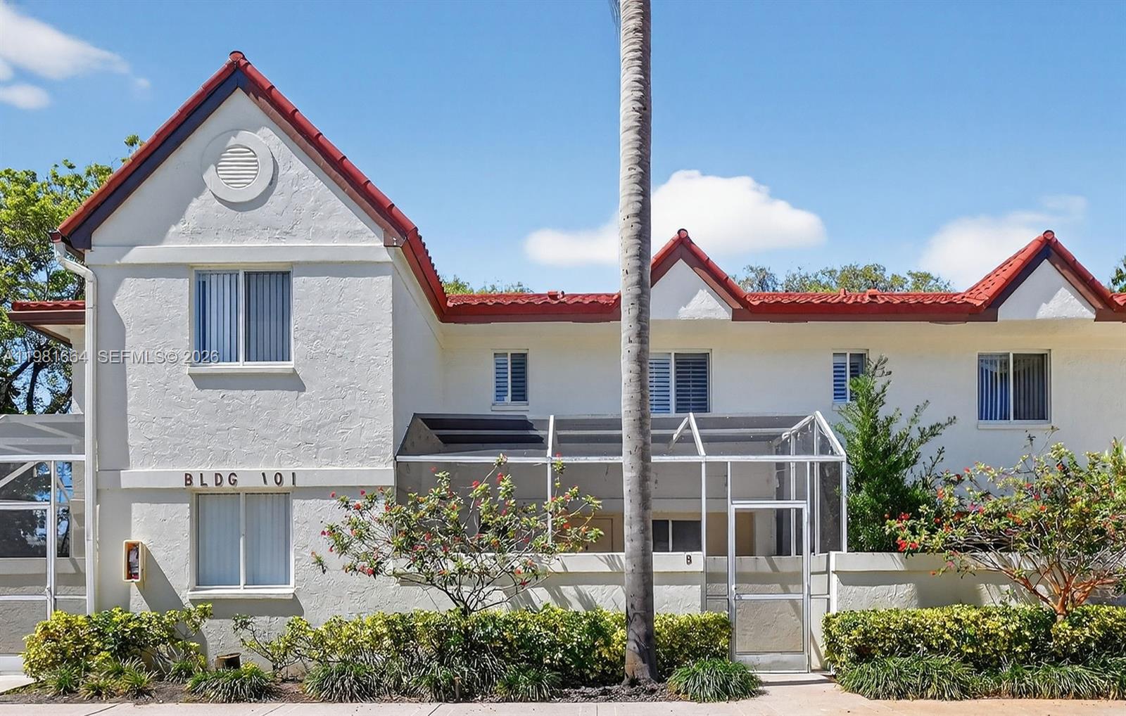 A two-story building with white stucco walls, red tile roofs, and a screened-in patio — 101 E Half Moon Cir # B, Hypoluxo FL 33462, HYPOLUXO, FL