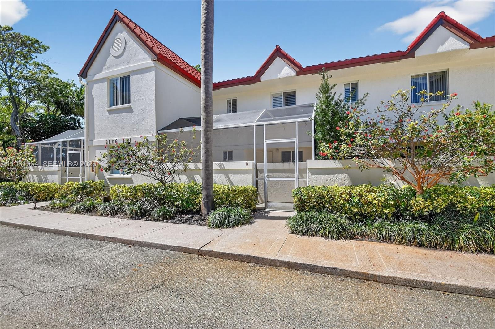 A two-story building with white stucco walls, red tile roofs, and screened-in entryways — 101 E Half Moon Cir # B, Hypoluxo FL 33462, HYPOLUXO, FL