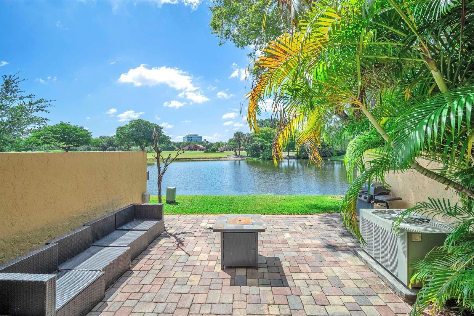 A paved patio features a fire pit, outdoor seating, and a view of a lake — 740 E Coco Plum Circle # 3, Plantation FL 33324, PLANTATION, FL