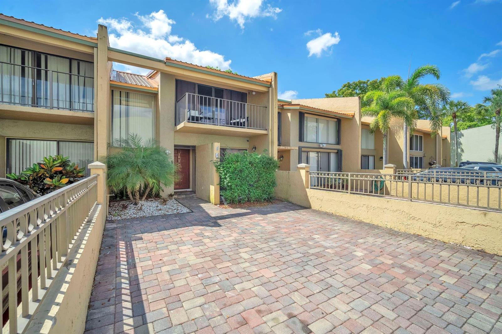 A paved driveway leads to the entrance of a two-story townhouse with a balcony — 740 E Coco Plum Circle # 3, Plantation FL 33324, PLANTATION, FL