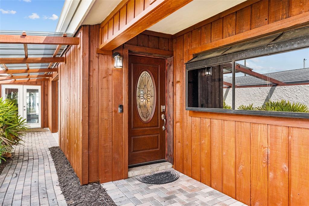 A wooden-sided house exterior features a front door with an oval glass insert and pavers — 10472 ORANGE BLOSSOM LANE, SEMINOLE, FL