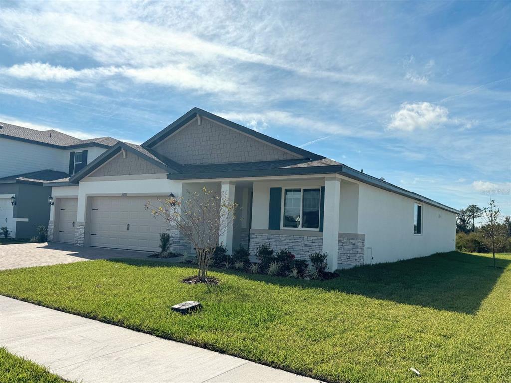 A single-story suburban house with a two-car garage, stone accents, and a manicured lawn — 36712 MELSTONE WAY, ZEPHYRHILLS, FL