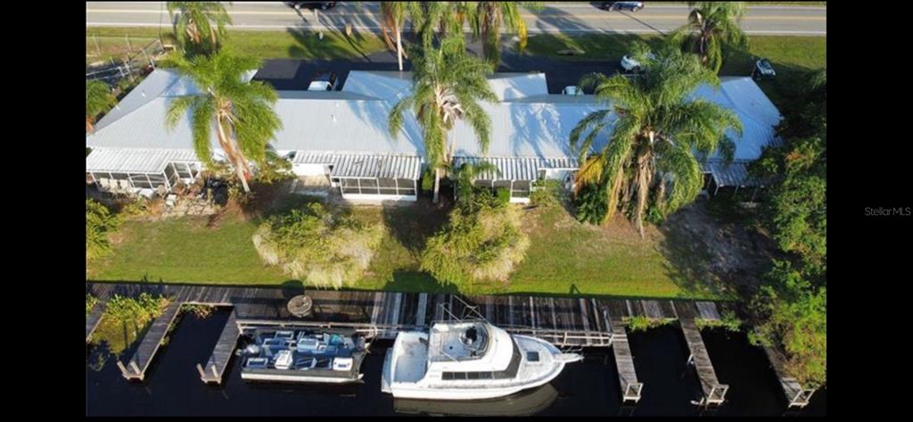 An aerial view shows a waterfront building with a dock, a boat, and palm trees — 26645 COUNTY ROAD 561 UNIT 3, TAVARES, FL