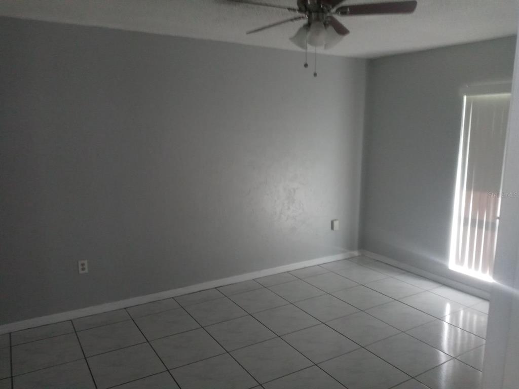 An empty room with gray walls, white tiled floors, and a ceiling fan — 26645 COUNTY ROAD 561 UNIT 3, TAVARES, FL