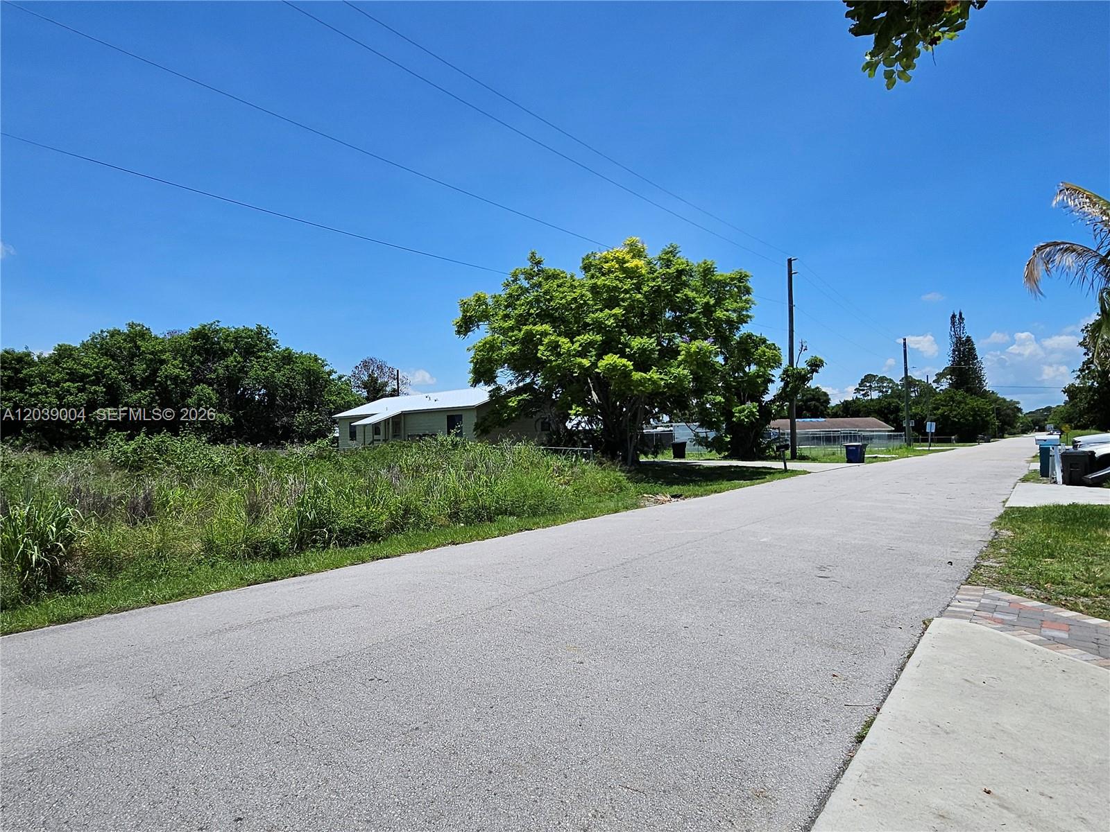 A paved road leads past a grassy lot with a large tree and a house — TBD San Marcos Ave, Fort Pierce FL 34946, FORT PIERCE, FL