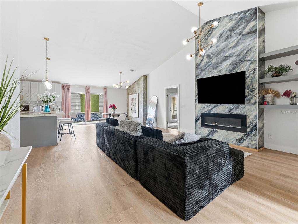 A modern living room features a black corduroy sectional, marble fireplace wall, and open kitchen — 530 RAPID FALLS DRIVE, BRANDON, FL