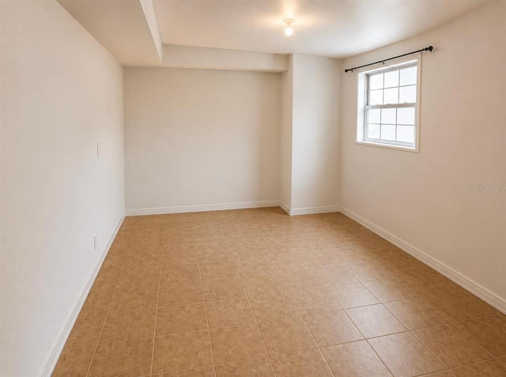 An empty room with beige tile flooring, white walls, and a single window — 301 CLARK STREET, MAITLAND, FL