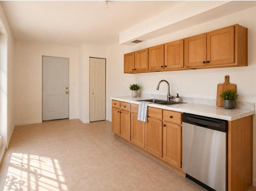 A kitchen features light wood cabinets, a stainless steel dishwasher, and a white countertop — 301 CLARK STREET, MAITLAND, FL