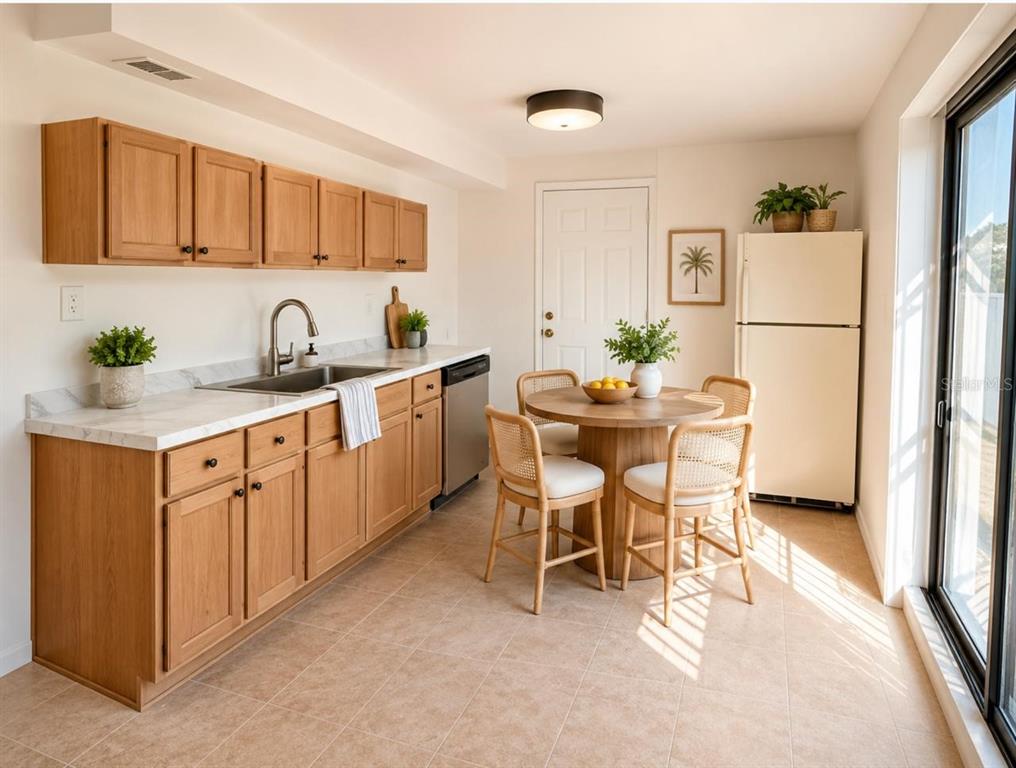 A kitchen with light wood cabinets, white countertops, a dining table, and a refrigerator — 301 CLARK STREET, MAITLAND, FL