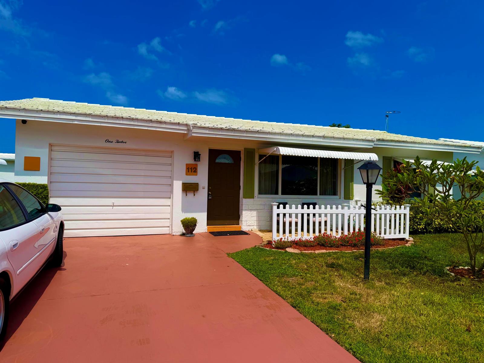 A single-story house with a white garage, brown door, and a small white picket fence — 112 SW 9th Street, Boynton Beach FL 33426, BOYNTON BEACH, FL
